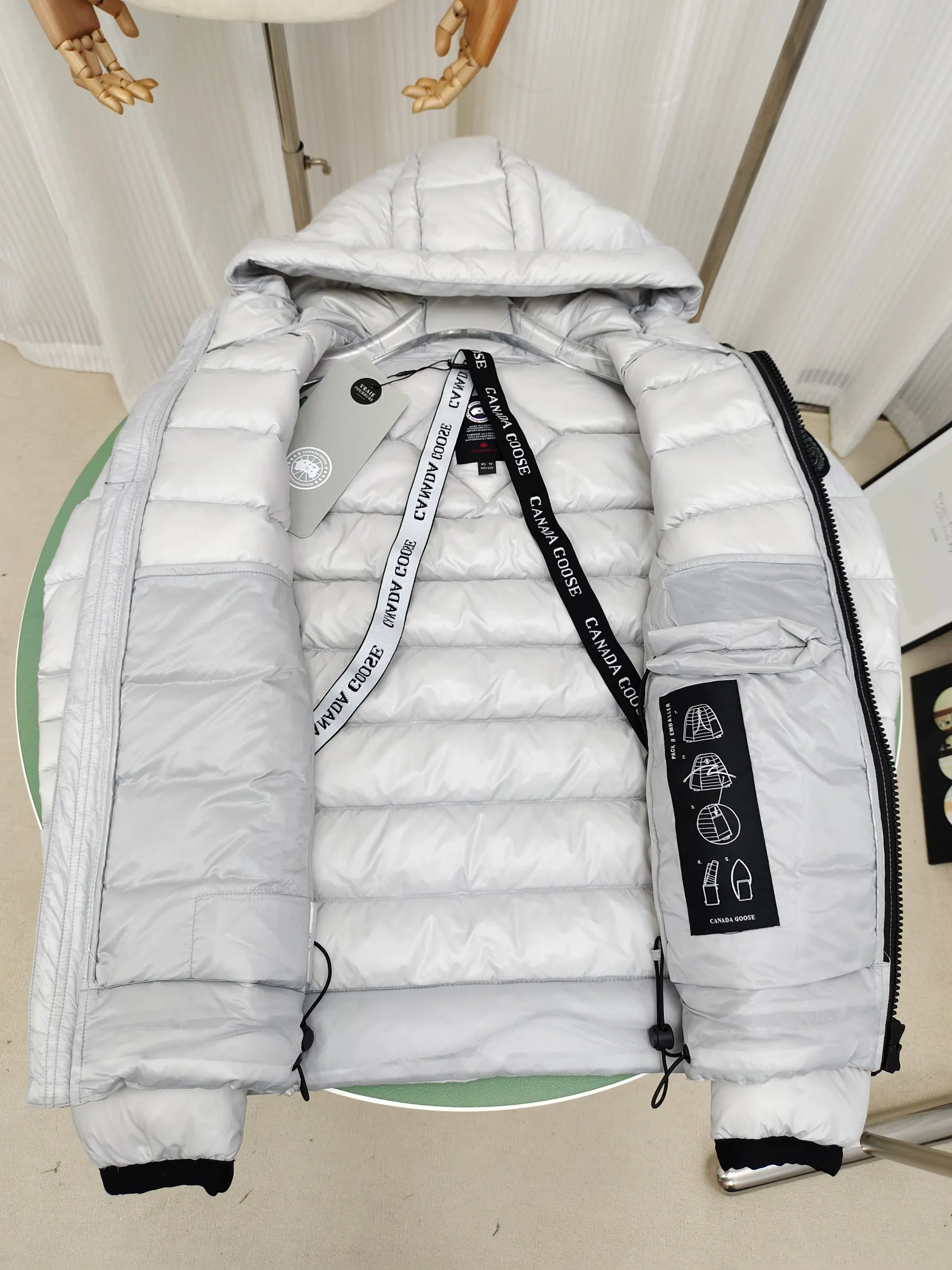P860 ————2227MB model (high version) Canada goose Crofton hooded down jacket, this is a down jacket suitable for late autumn and early winter: on cold, rainy mornings, it can be used as a layer of warmth inside the rainproof jacket, and can be worn alone in the late autumn and early winter with a little bit of coolness. Filled with white duck down. The Crofton Hooded Jacket is a versatile, lightweight and versatile piece that even packs itself in for easy transport. The inner layer has removable elastic straps, making the jacket easy to carry on the shoulder and hands-free. 2 zippered hand pockets with fleece fabric on the knuckle side for softness and warmth. Color: black with black label, black with red label, ocean blue, superoxide blue, silver birch red label, silver birch black label Size: XS-2XL